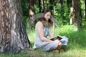 beautiful-girl-dress-sitting-under-tree-grass-reading-book-52635232